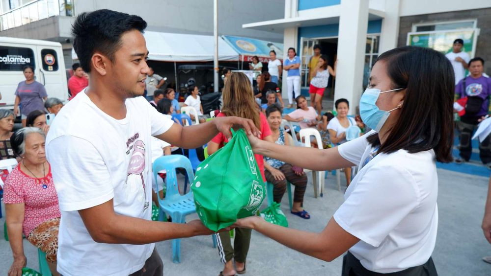 A_volunteer_employee_from_SM_City_Calamba_right_hands_out_aid_supplies_to_a_beneficiary_of_Operation_Tulong_Express_OPTE