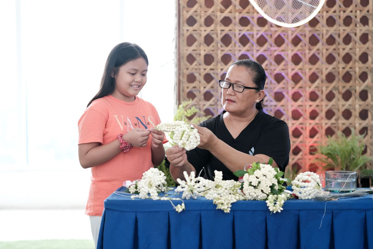 A_young_shopper_learns_the_art_of_Sampaguita_garland_making_from_a_San_Pedro_Sampaguita_maker