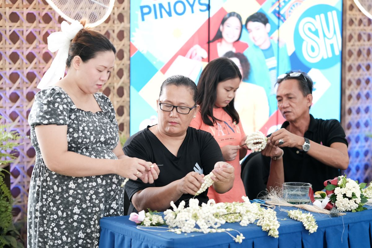 Stanley_Oriondo_and_Veronica_Berroya_sampaguita_makers_from_San_Pedro_teach_mall_shoppers_to_thread_the_Sampaguita_buds_into_leis
